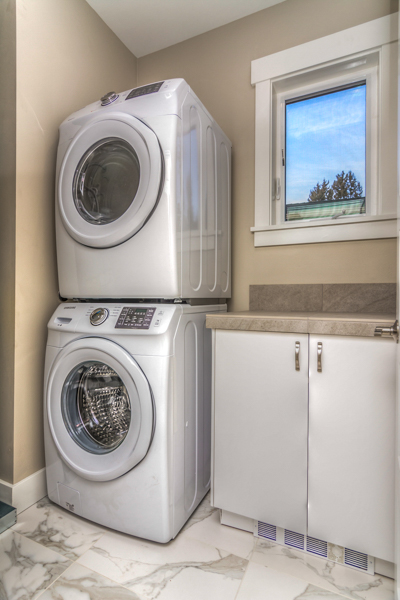 The laundry room in this west side executive condo includes a stacking washer and dryer