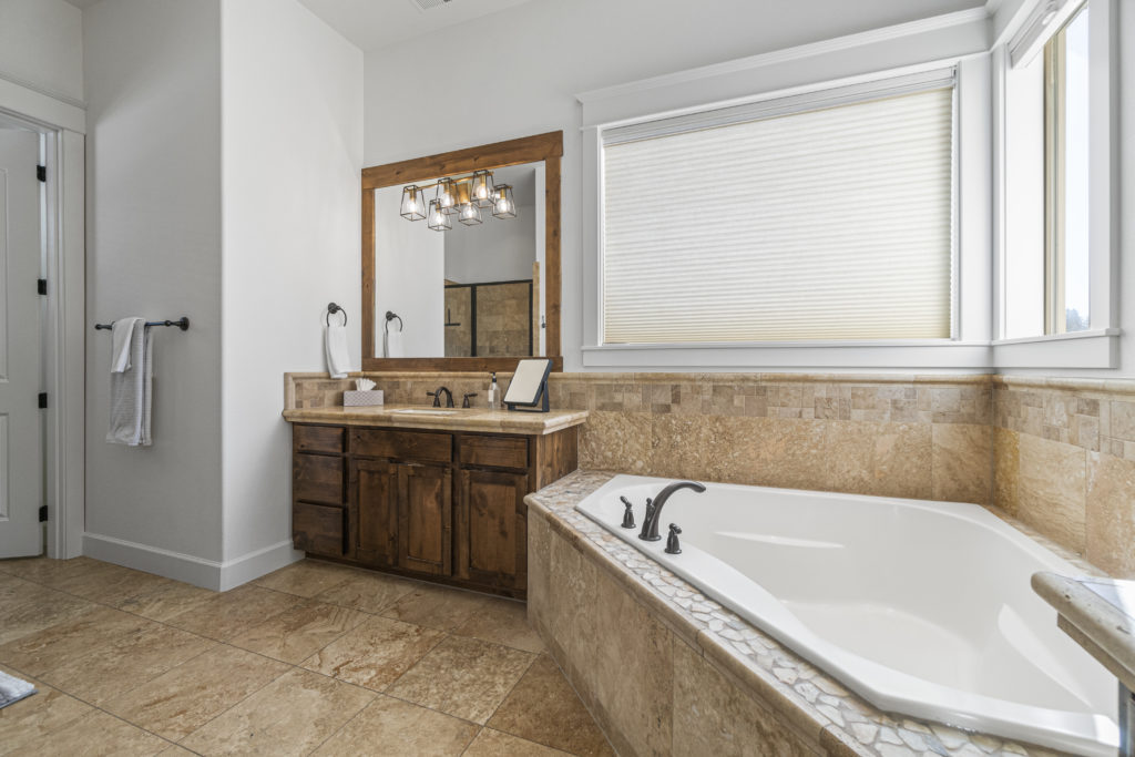 The primary en suite of this furnished home in Bend includes a large soaking tub..